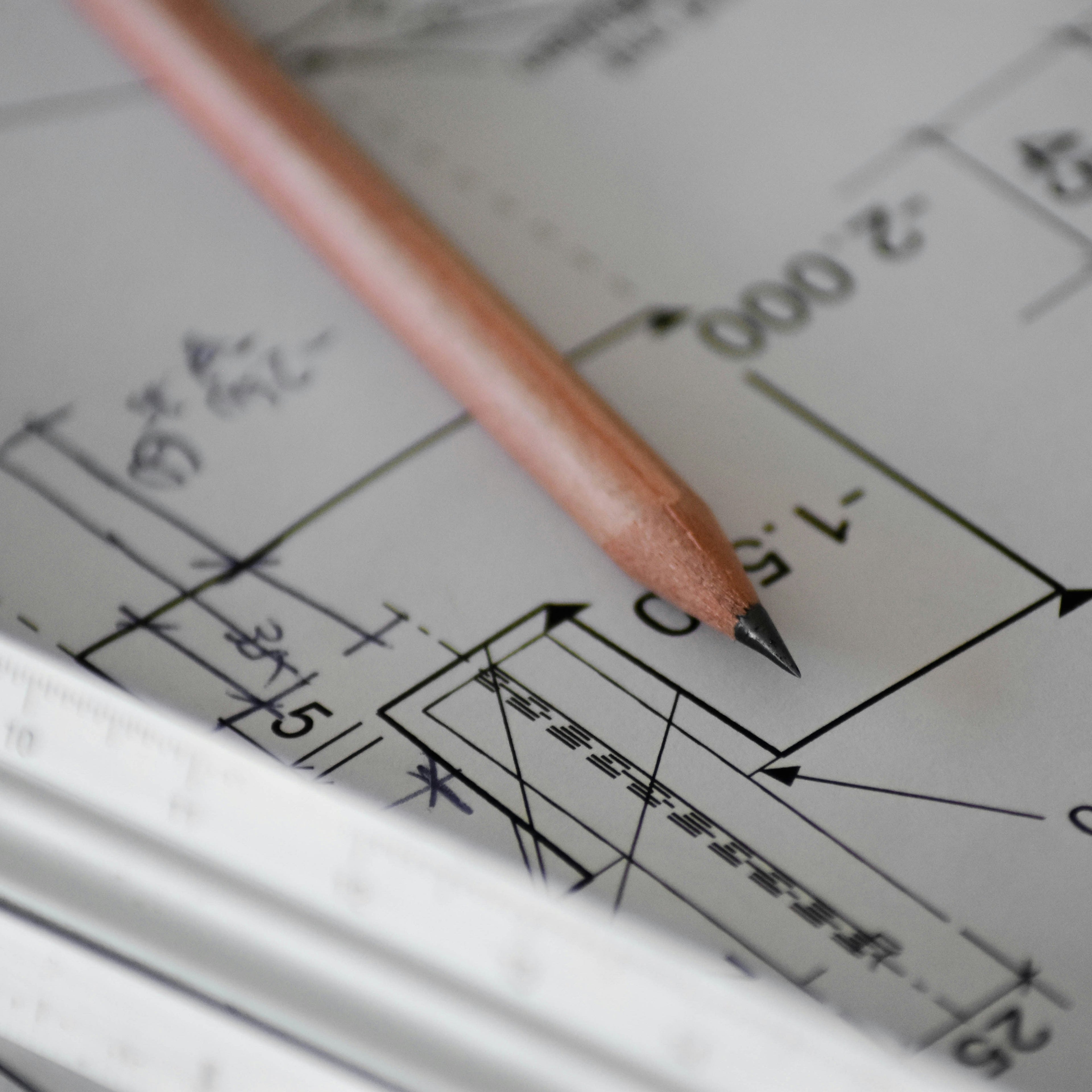 A pencil resting on top of a detailed floor plan drawing.